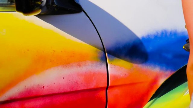 Spray painting the side of a car in slow motion.