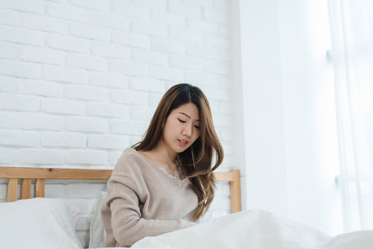Portrait beautiful young Asian woman on bed at home in the morning. Cheerful Asian woman wearing a comfortable sweater and smiling on her bed. Relaxing room. lifestyle asia woman at home concept.