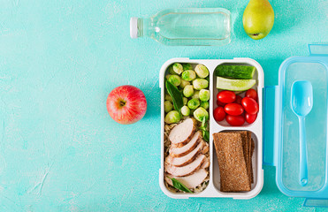 Healthy green meal prep containers with chicken fillet, rice, brussels sprouts and vegetables overhead shot with copy space. Dinner in lunch box. Top view. Flat lay © timolina