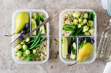 Vegan green meal prep containers with  rice, green beans,  brussel sprouts, cucumber and fruits....