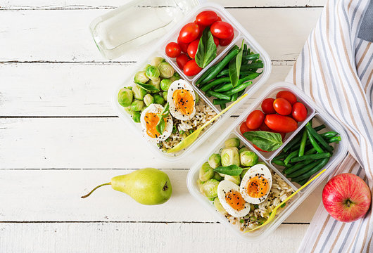 Vegetarian meal prep containers with eggs, brussel sprouts, green beans and tomato. Dinner in lunch box. Top view. Flat lay