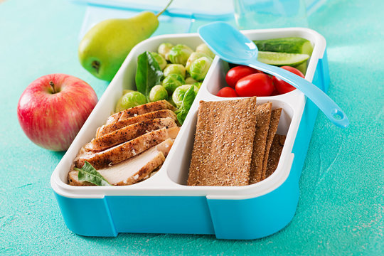 Healthy green meal prep containers with chicken fillet, rice, brussels sprouts and vegetables overhead shot with copy space. Dinner in lunch box.