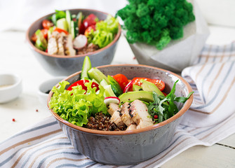 Buddha bowl dish with chicken fillet, quinoa, avocado, sweet pepper, tomato, cucumber, radish, fresh lettuce salad and sesame. Detox and healthy superfoods breakfast bowl concept.