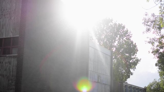 A nice tilt from a run-down school to the beautiful sky with a glare of the sun.