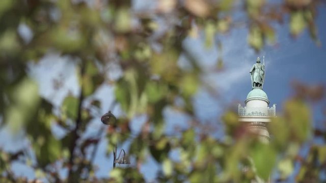 The statue of Saint-Louis on the Colonnes du trone at the Place de la Nation in Paris with leaves in the foreground