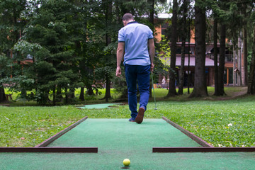 a man in blue clothes goes to the place of impact for playing mini-golf