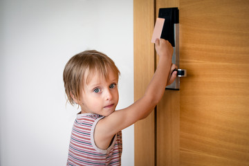 Little boy trying to open doors with card lock at the hotel, holding by hinge