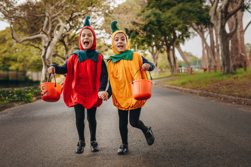 Cute little girls trick or treating in halloween costume - obrazy, fototapety, plakaty