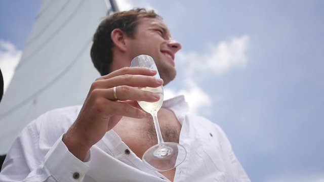 A rich life, a man in a white shirt with a hairy chest, drinks champagne while standing on a yacht. slow motion, HD, 1920x1080