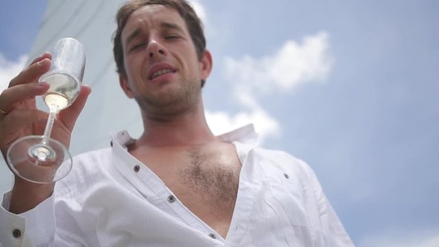 A life of luxury, a man in a white shirt with a hairy chest, drinking champagne while standing on a yacht. slow motion, HD, 1920x1080