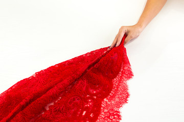 Hand pulls a red fabric with lace