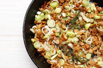 Chanterelles fried with leek in a pan