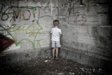 A little boy is standing in the corner as a punishment.