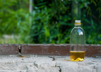 Bottle with yellow liquid on the old brickwork.