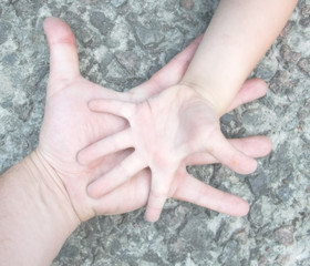 The hand of a man and a boy: father and son on the background of stones.