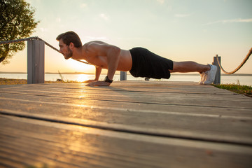 Picture of a young athletic man doing push ups outdoors