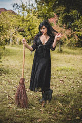 Gothic lady in a glamorous vintage look for Halloween, witch with a broom. Beautiful citizen in vintage clothing pretty accessories of handmade work. Ideas for the Halloween holiday