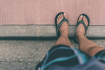 Male feet on black sandals on a smooth red textured background