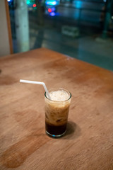 A glass of ice espresso coffee on wooden table in restaurant.