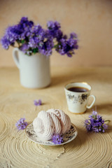 Homemade marshmallow on a saucer with appliances and a Cup of coffee, on a light background with purple flowers. The concept of a cozy autumn dessert.
