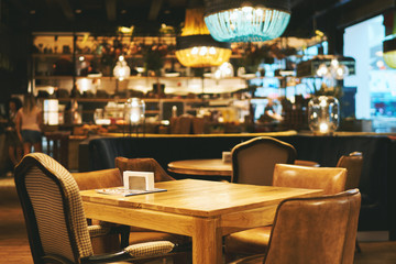 Fototapeta na wymiar Blurred restaurant or cafe background. Tables and chairs. Visitors to the family restaurant for dinner. Beautiful bright interior. Blurred background bokeh background for design 