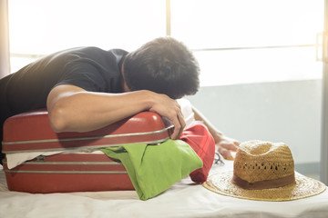 man trying to fit all clothing to packing his red suitcase before vacation.