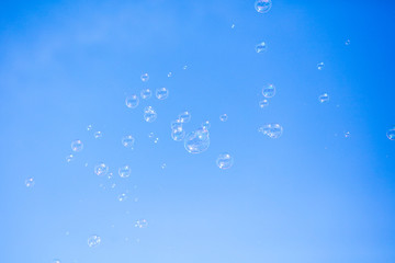 Soap bubbles in flight against the blue sky