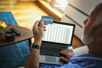 Senior man doing online shopping while sitting at home