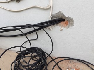 break in the wall with protruding electrical wires, Electric wire sticking out of a white wall, crack hole wall with electric wires