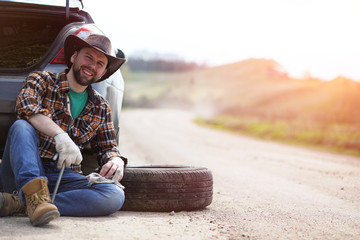 Man is sitting on the road by the car