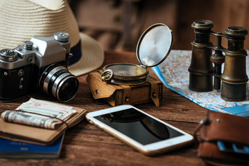 Fototapeta na wymiar Mobile phone with blank screen on wooden table background. Looking image of traveling concept.