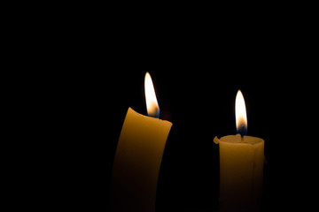 Two burning candles on black background
