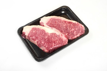 Raw steak in an airtight vacuum package on a white background.
