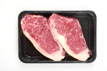 Raw steak in an airtight vacuum package on a white background.