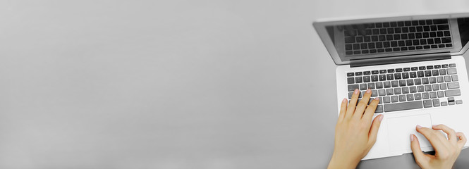 Website banner of top view laptop and female hands with copyspace in grey color background. Concept...