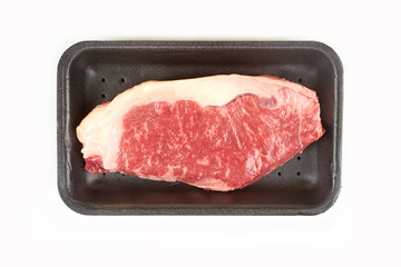Raw beef steak in a tray isolated on white background.