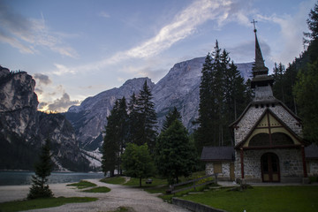 Fototapeta na wymiar View of small chapel/church or Cappella Lago di Braies by tourist popular lake Lago di Braies (Pragser Wildsee) in summer. Dolomites mountains, Sudtirol, Italy