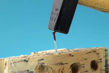 A some worker using hammer to slamming the nail to wooden board.