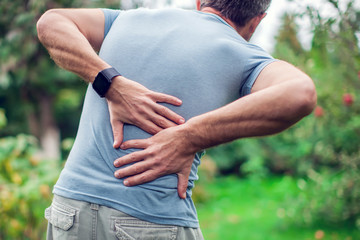 People, healthcare and problem concept - unhappy man suffering from pain in back or reins outdoor