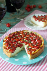 Tart, pie or cheesecake with cottage cheese and tomatoes, served with red wine on a wooden background.
