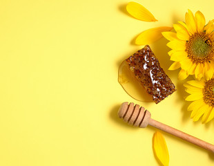 Sunflower with  honeycomb and honey dipper on yellow background. Top view with copy space