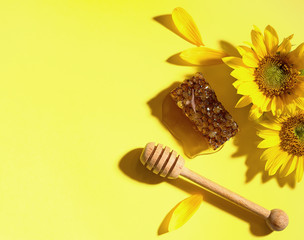 Sunflower with  honeycomb and honey dipper on yellow background. Top view with copy space