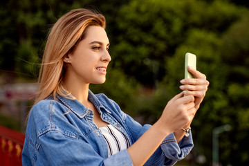 beautiful fashion girl doing selfie with phone at sunset