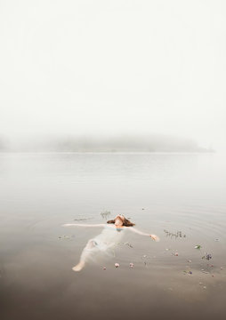Young woman floating on water in mist