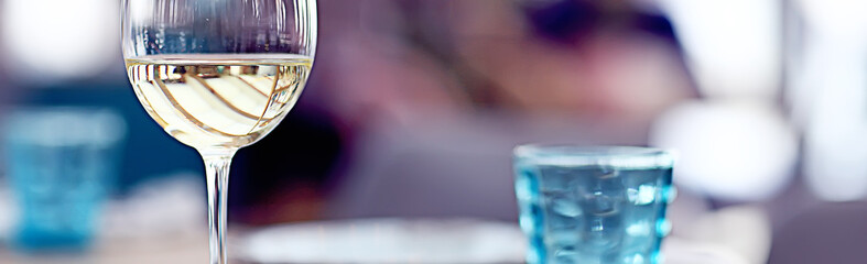 glass of white wine in the restaurant / white wine in the interior of the restaurant a table with...