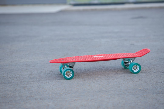 Red penny board is on the road, close-up. Skateboard and space for text.