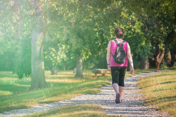 Middle age woman walking in a park, outdoor quiet stroll (image with copy space)