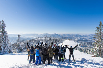 A group of people stands on top of the mountain in the winter