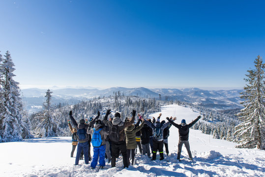 A group of people stands on top of the mountain in the winter