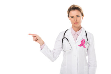 doctor with pink ribbon pointing with finger and looking at camera isolated on white, breast cancer...